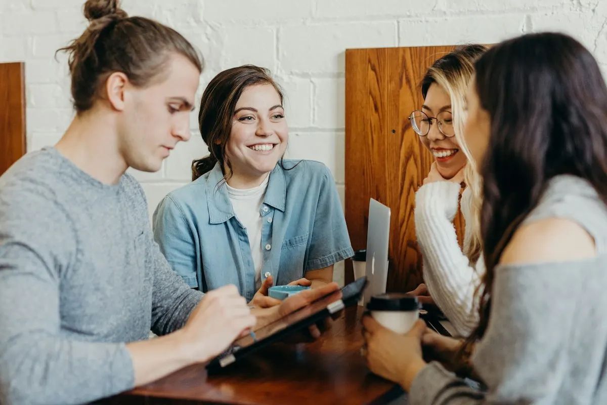 Quatre apprenants souriants échangent autour d’une tablette pendant une formation